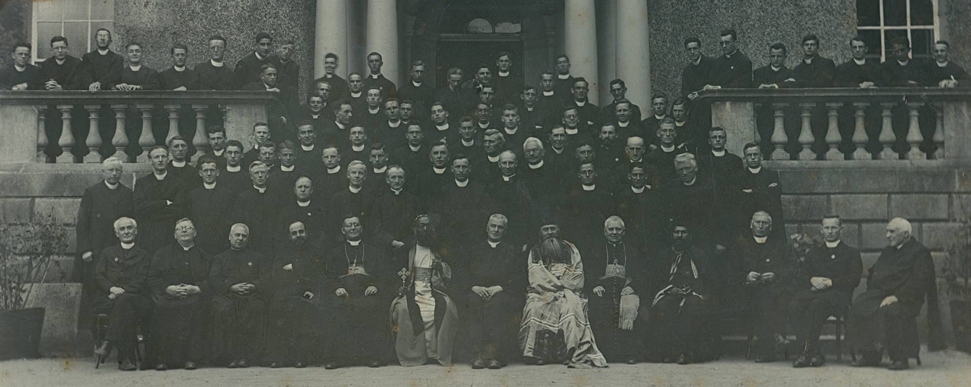 Jesuit community at Rathfarnham Castle, 1932 The Jesuit commnuity at Rathfarnham Castle on the occasion of the International Eucharistic Congress. Includes: Fr. T.V. Nolan SJ (Rector) and Irish Jesuits resident at Rathfarnham with guests; Mar Ivanios, Archbishop of Trivandrum, India; Bucys, Bishop of Olympus; Broderick, Bishop Peduelli; Trurita y Alumandos, Bishop of Barcelona; Rector of the Armenian Mission in Paris and Fr. Griffith, Vancouver. Rev. D.D. Ivanios and Bucys celebrated massess according to their respective Eastern rites in the chapel at Rathfarnham. FM/RATH/71. Courtesy of the Irish Jesuit Archive. 